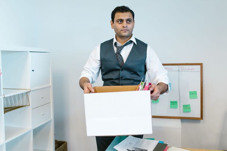 Mann räumt Büromaterial in einen Umzugskarton.